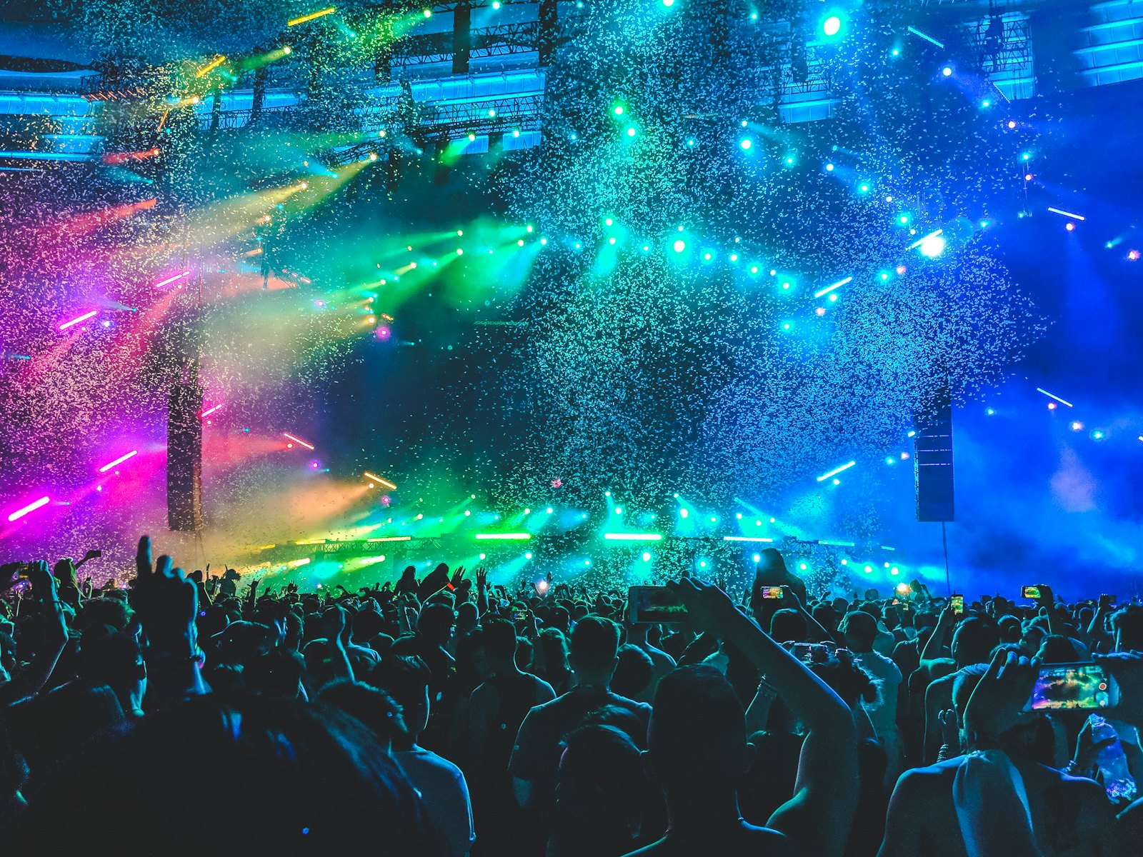 A colorful festival crowd under confetti and stage lights